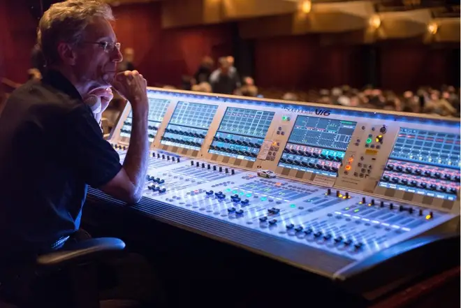 Audio engineer operating a professional mixing console at a live event — illustrative real photograph
