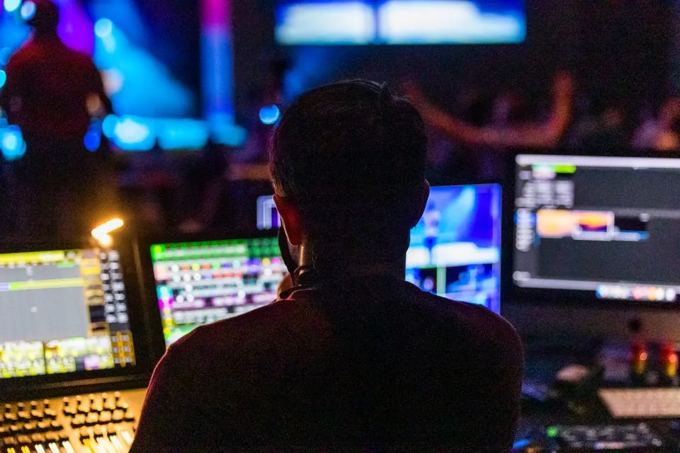 Live event production operator working at multiple control screens — real photograph
